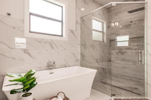 a bathroom with a tub and a glass shower at Luxury Naples 4br W Pool Near Vanderbilt Beach in Naples