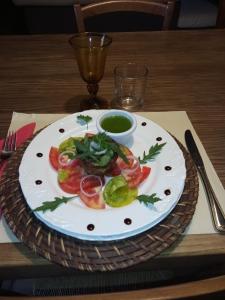 une assiette avec des tomates et un bol de sauce sur une table dans l'établissement Maison D'hôte -Au Balcon De L'Obiou, à Les Cotes de Corps