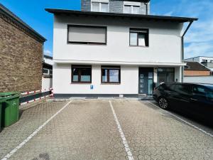 a car parked in front of a white house at RheinZeit Apartment Köln Bonn in Niederkassel