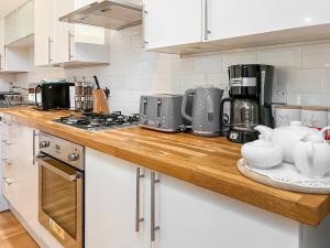 プリンプトンにあるThe Granary Houseの白いキャビネットと木製のカウンタートップを備えたキッチン +9枚の写真