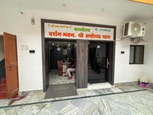 an entrance to a building with a person sitting inside at Omji - Darshan Bhawan - 2km from Ram Janmbhumi Temple in Ayodhya
