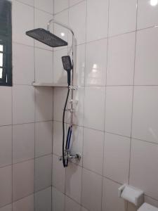 a shower with a blow dryer on a white tiled wall at EAR KEN BARHAM GUESTHOUSE in Rwumba