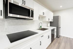 a white kitchen with a microwave and a sink at Jnice Residence in Windsor