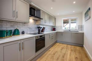 Countryside Hot Tub Games Area في Bunny: مطبخ بدولاب بيضاء وأرضية خشبية