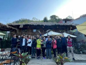 un groupe de personnes posant une photo devant une maison dans l'établissement Mộc HomeStay Trạm Tâu, à Trạm Tấu