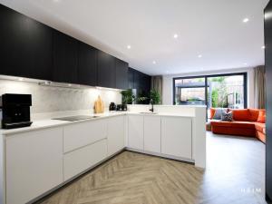 una cucina con armadi bianchi e un divano arancione di Eden at The Heim Residences a Manchester