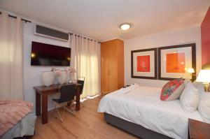 a bedroom with a bed and a desk with a computer at The Sleep Easy in the Old Town Stellenbosch in Stellenbosch