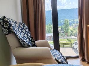 a chair with a blanket sitting in front of a window at soltanisha in Mestia