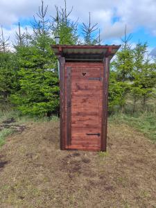 a wooden outhouse sitting in the middle of a field at Mardi talu Glamping 