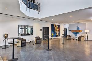 a room with tables and chairs and paintings on the wall at Four Points Flex by Sheraton Ratingen Düsseldorf Airport in Ratingen