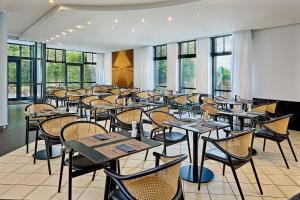 a dining room with tables and chairs and windows at Four Points Flex by Sheraton Ratingen Düsseldorf Airport in Ratingen