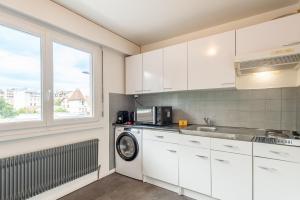 a kitchen with white cabinets and a washing machine at M061 Marquer Joli Studio chaleureux in Annemasse