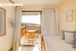 a bedroom with a bed and a balcony with a table and chairs at Estúdio prático e aconchegante no VG Sun in Paracumbuca +45 photos