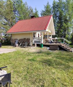 a small house with a red roof and a deck at Toivon pieni rantamökki in Sonka