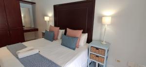 a bedroom with a bed with pink and blue pillows at Studio 14 @ The Dunes in Plettenberg Bay +4 photos