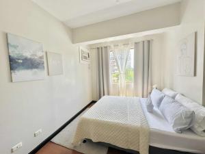 a white bedroom with a bed and a window at Magallanes Residences Condominium 211&212B in Davao City +111 photos