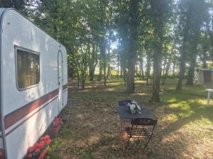a table next to a trailer in the woods at Chez Vallye in Maxent