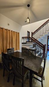 a dining room with a table and chairs and stairs at Shree Gowthameshwara Nilaya in Chikmagalūr