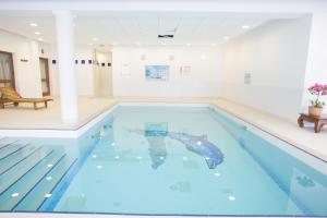 a large swimming pool with blue water in a building at Les Gentianes by Actisource in Puy-Saint-Vincent
