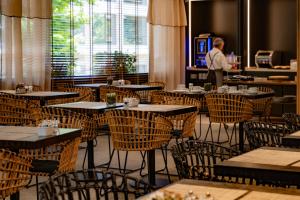 a restaurant with tables and chairs with a man standing in the background at Hotel Dom Carlos Park in Lisbon