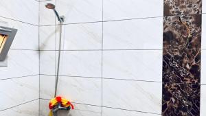 a shower with a hose on a white tile wall at Tulivu Rëcc in Nditarh