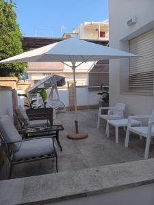 a patio with chairs and an umbrella and a swing at Villetta Angela in Torre San Giovanni Ugento