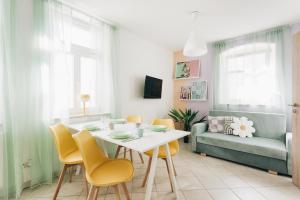 un soggiorno con tavolo, sedie e divano di Creekside Colors - Playful Apartment a Löbau