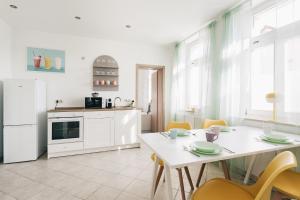 a kitchen with a white table and yellow chairs at Creekside Colors - Playful Apartment in Löbau