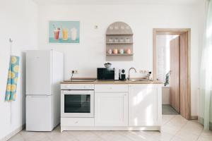 una cucina bianca con frigorifero e lavandino di Creekside Colors - Playful Apartment a Löbau Altre 13 foto