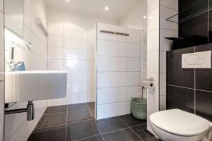 a white bathroom with a toilet and a sink at Appartement De Kokkel Free Parking in Zandvoort