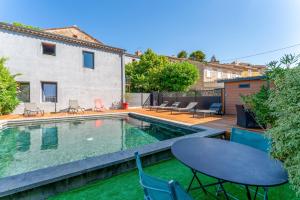 un patio trasero con piscina, mesa y sillas en Côté cour, en Rasteau