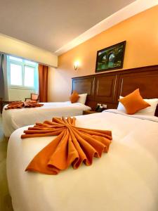 Una habitación de hotel con dos camas con almohadas naranjas. en Aracan Hotac Ras El Bar, en Ras El Bar