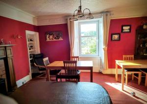 a dining room with red walls and a table and a window at Broomfield House Bed and Breakfast in Earlston