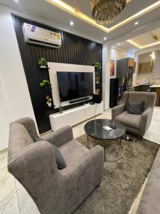 アクラにあるRosewood residence 2 bedroom duplex with views and bathtubの椅子2脚とテレビのあるリビングルーム