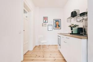 uma cozinha com armários brancos e piso de madeira em Einzigartiges Design Apartment em Löbau
