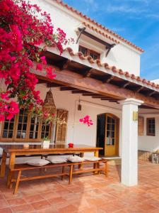 a patio with two benches in front of a house with pink flowers at Authentic Villa with amazing pool in Santa Gertrudis de Fruitera
