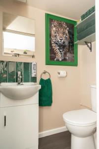 a bathroom with a painting of a leopard on the wall at Jungle Lodge in Rustington +21 photos