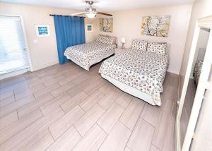 a bedroom with two beds and a wooden floor at Sea Breeze 101 Beach Bliss in St Pete Beach +20 photos