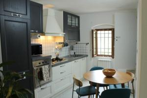 a kitchen with black cabinets and a table with chairs at Private Room in Chianti Shared Home in San Pancrazio