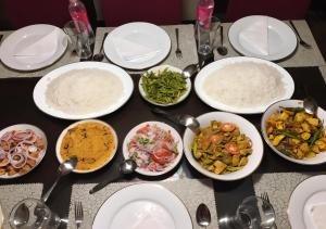 a table topped with white plates and bowls of food at Heritage Haven in Kandy