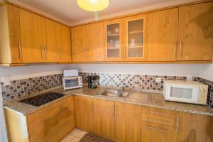 a kitchen with wooden cabinets and a sink and a microwave at Le bourg 2 in Mimizan +3 photos