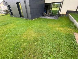 a yard with green grass in front of a building at My HOME in Arlon