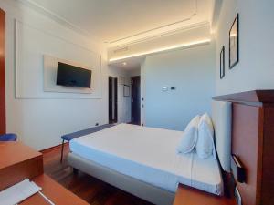 a bedroom with a large white bed and a desk at Dado Hotel International in Parma +61 photos