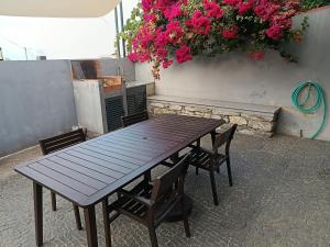 a wooden picnic table with two chairs and pink flowers at A Casa do Encanto da Ana & Luis in Ponta do Sol