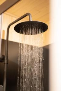 a shower with water coming out of it at Tiny-House en Nature - Salle de bain italienne - Lit king Grand confort in Le Luc