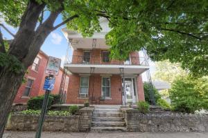 uma casa de tijolos vermelhos com uma varanda e escadas na frente em Spacious Historic 8-Bedroom Manor in Short North - Perfect for Large Groups em Milo mais 101 fotografias