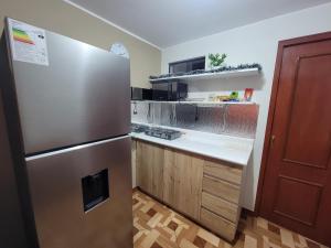 a kitchen with a stainless steel refrigerator and wooden cabinets at Departamento, LUJO HOGAR cerca a PLAZA NORTE - UNI AEROPUERTO in Lima