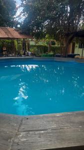 a large blue swimming pool with a tree in the background at Pousada Casa Verde in Cordisburgo