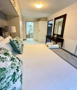 una camera da letto con un grande letto bianco e una scrivania di The Lemon Tree Self Catering Cottage a Bloemfontein