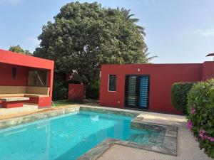 - une piscine en face d'une maison rouge dans l'établissement Villa Kër Noflaye - Saly, à Sintiân 6 autres photos